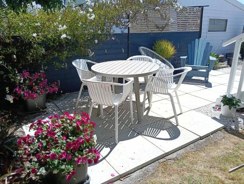 a table and chairs and flowers on a patio at Omanu Cottage in Mount Maunganui