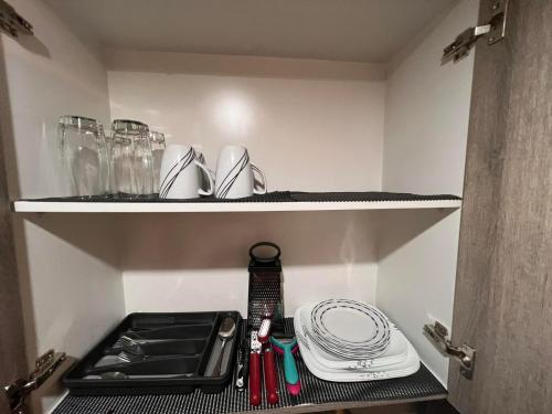 a kitchen cabinet with a sink and plates and utensils at SMDC Coast Residences by Presto Real Estate Management near MOA, PICC, Star City and NAIA in Manila