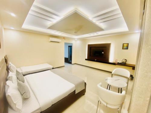 a white bedroom with a bed and a tv at Ayansh Klyde Inn, Lucknow in Lucknow
