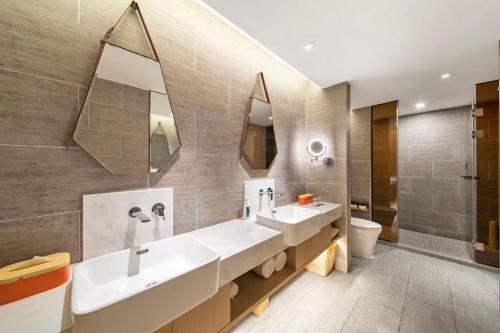 a bathroom with two sinks and a toilet and mirrors at Atour Hotel Ya an Era Street in Ya'an
