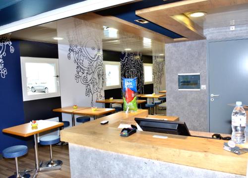 ein Restaurant mit einer Bar mit Holztischen und -stühlen in der Unterkunft ibis budget Flers Grands Champs in Flers