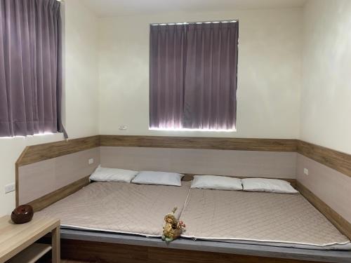 a bed in a room with two windows at Hakka Eco-farm 雅歌園民宿食農教育有機農場 in Wanluan