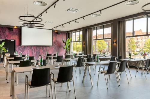 a conference room with tables and chairs and a projection screen at Apollo Hotel Amsterdam, a Tribute Portfolio Hotel in Amsterdam