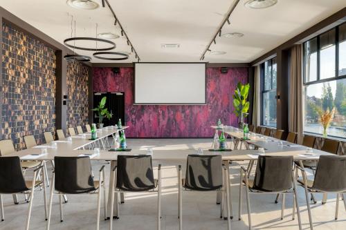 a conference room with tables and chairs and a projection screen at Apollo Hotel Amsterdam, a Tribute Portfolio Hotel in Amsterdam