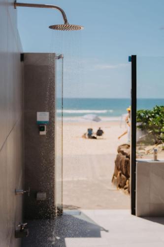 a bathroom with a shower with the beach in the background at On The Beach Noosa Resort in Noosa Heads
