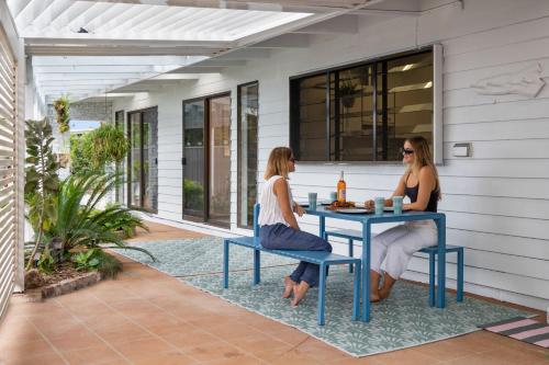 two women sitting at a table on a patio at Pumicestone Beach House - 200m to the passage in Pelican Waters