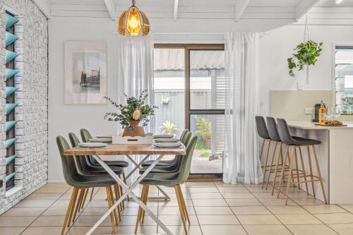 a kitchen and dining room with a table and chairs at Pumicestone Beach House - 200m to the passage in Pelican Waters
