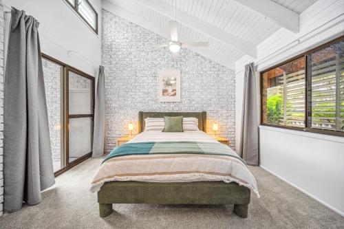 a bedroom with a bed and a brick wall at Pumicestone Beach House - 200m to the passage in Pelican Waters