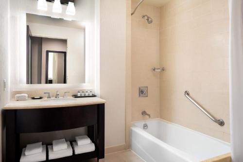 a bathroom with a sink and a tub and a mirror at Sheraton Garden Grove-Anaheim South in Anaheim