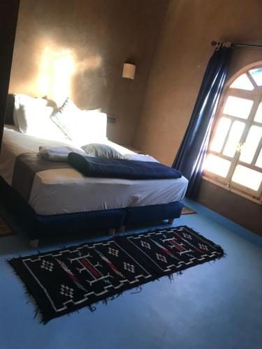 1 dormitorio con 1 cama con alfombra y ventana en Dar Talhaya, en Oulad Driss