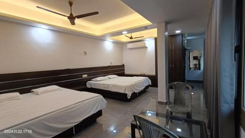 a hotel room with two beds and a glass table at Aroma Serviced Villa Cochin in Ernakulam
