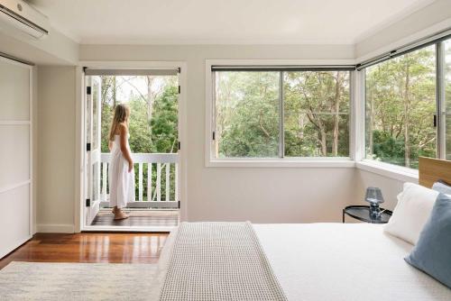 a woman standing on a porch looking out of a bedroom window at Bangalow Retreat in Buderim in Buderim