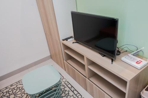 a flat screen tv sitting on a wooden entertainment center at Cozy and Spacious 1BR Apartment at Parkland Avenue By Travelio in Tangerang