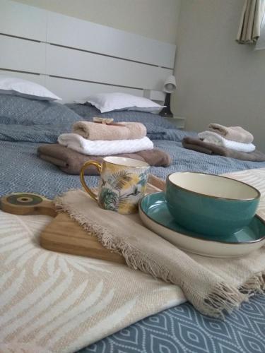 a table with a bowl and a plate on a bed at Maya Apartman in Szeged