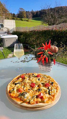 a pizza on a table next to a glass of wine at La Maisonnette Enchantée in Prez-vers-Siviriez