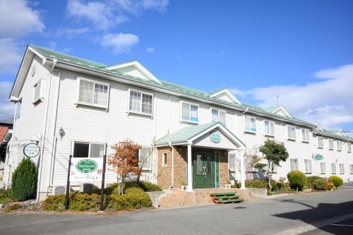 a white building with a green door on a street at やすらぎの宿フォーシーズン矢本 in Yamoto