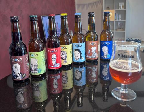 a group of beer bottles on a table with a glass of beer at La Maisonnette Enchantée in Prez-vers-Siviriez