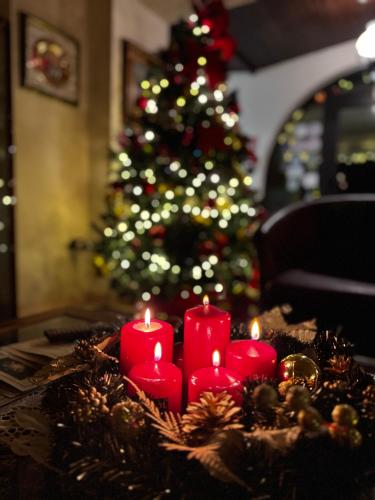 a group of red candles on a table with a christmas tree at Hotel Ristorante La Grotta in Castiglione delle Stiviere