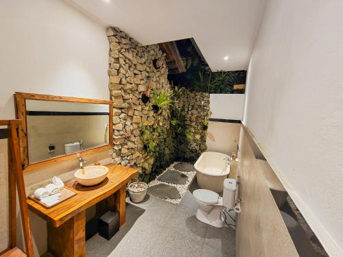 a bathroom with a toilet and a sink and a mirror at Uma Jala Villa Ubud in Ubud