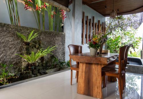 a wooden table and chairs in a room with plants at Uma Jala Villa Ubud in Ubud