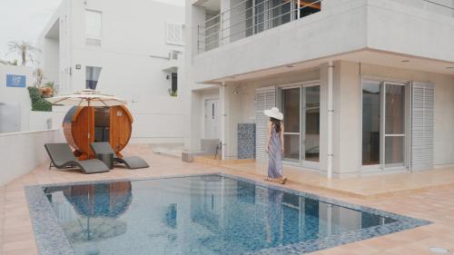 a woman standing next to a swimming pool next to a building at Villa Sirene Ishigaki in Ishigaki Island