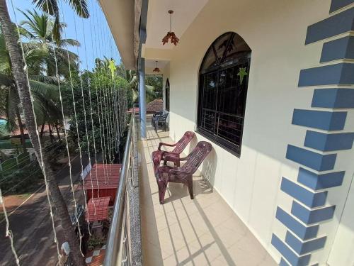 two chairs sitting on the balcony of a house at Whispering Waves Luxury Homes in Majorda