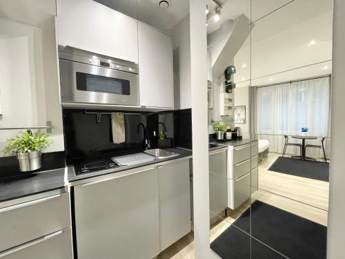 une cuisine avec des armoires blanches et des appareils en acier inoxydable dans l'établissement Charming Studio Paris la Défense, à Puteaux