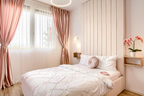 a bedroom with a white bed and a window at ARI - AFI Mall Luxurious Apartments with Free Parking in Arad