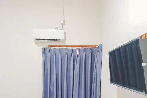 a room with a heater and a blue curtain at RedDoorz at Anjasmoro Guest House near Bandara Ahmad Yani Semarang in Kalibanteng-lor