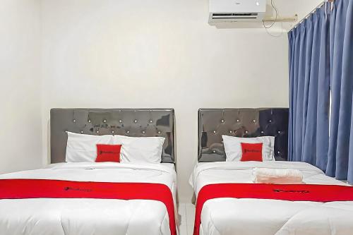 two beds sitting next to each other in a bedroom at RedDoorz at Anjasmoro Guest House near Bandara Ahmad Yani Semarang in Kalibanteng-lor