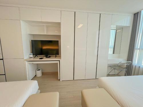 a bedroom with a tv and a desk with a computer at UH FLAT The SONGDO in Incheon