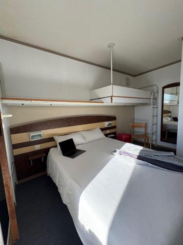 a bedroom with a white bed with a laptop on it at FastHotel Montpellier Ouest - Un Hôtel FH Classic in Saint-Jean-de-Védas