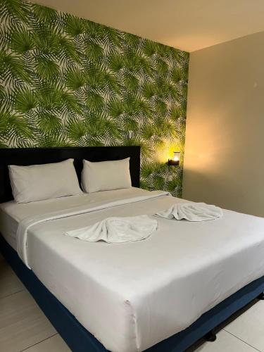 a large bed with white sheets and a green wall at HOTEL SRI SUTRA (BANDAR SUNWAY) in Petaling Jaya