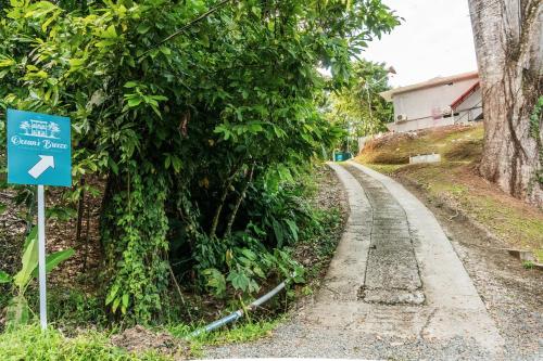 a road with a blue sign next to a tree at Ocean's Breeze Apartment and Rooms in Puerto Viejo