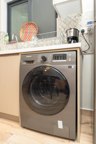 a washing machine sitting under a counter in a kitchen at Elite Residence 7 Star Luxe Condo with Gym and Pool next to JW Marriott, Westlands Airport Shuttle, Luggage Storage available in Nairobi