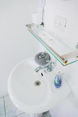 a white bathroom with a sink and a mirror at Ocean's Breeze Apartment and Rooms in Puerto Viejo