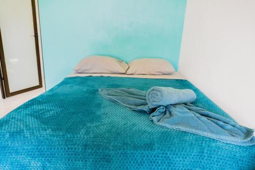 a bed with a blue blanket and a towel on it at Ocean's Breeze Apartment and Rooms in Puerto Viejo