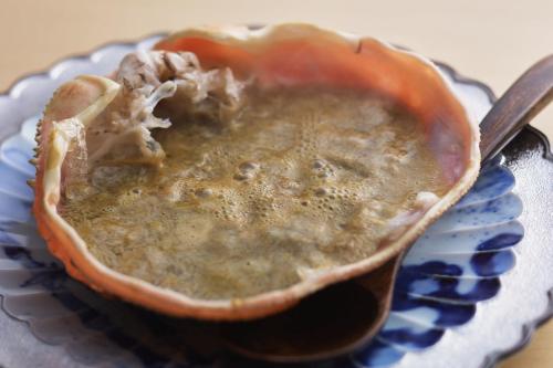 a bowl of soup on a plate with a spoon at TSUCHIYA Kinosaki onsen in Toyooka
