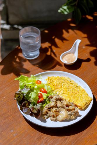 a plate of food with a salad and a sandwich at Siam Plug In Hostel in Bangkok