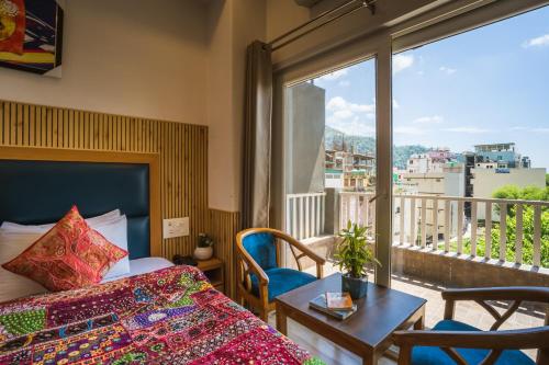 a hotel room with a bed and a table and a window at Tripli Hotels Ayushman Retreat in Rishīkesh