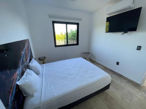 a white bedroom with a bed and a window at Mahaguay - Bello dto frente al mar in Mahahual
