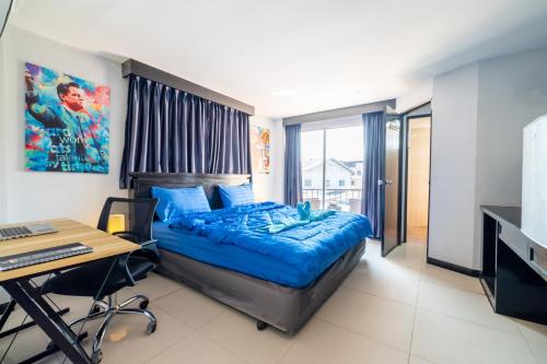 a bedroom with a bed and a desk and a computer at Abunawas Merry Inn at Walking Street in Pattaya South