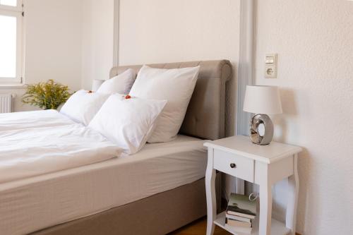 a bed with white pillows and a table with a lamp at Gästehaus am Winckel in Stendal