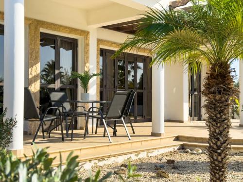 a patio with a table and chairs and a palm tree at Beachfront Villa with Private Pool and Exotic Fruit Garden in Pyla