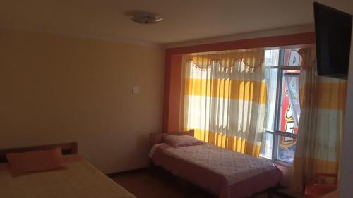 een slaapkamer met twee bedden en een raam bij Hospedaje Vista al Lago in Puno