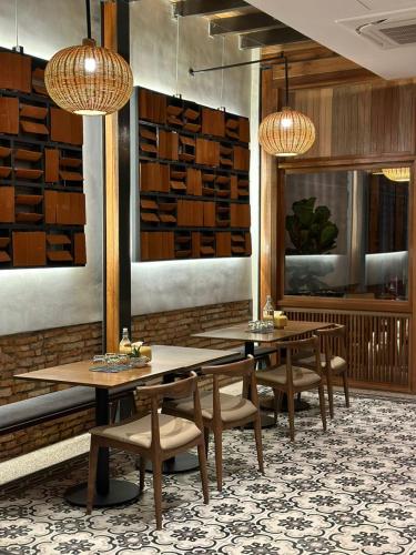 a dining room with two tables and chairs and lights at Baba House Melaka in Melaka