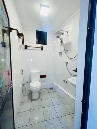 a white bathroom with a toilet and a sink at Villa Bellissimo - Hiriketiya in Dickwella