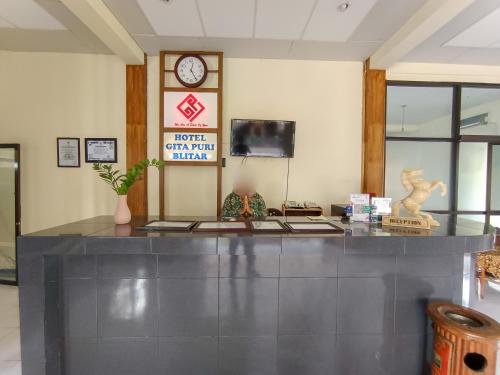 a lobby with a counter and a clock on the wall at Gita Puri RedPartner Blitar in Blitar