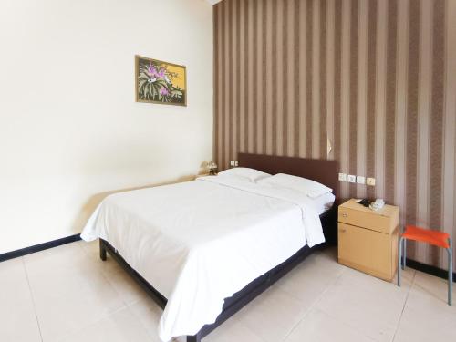 a bedroom with a large white bed and a table at Gita Puri RedPartner Blitar in Blitar