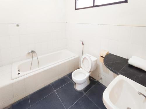 a bathroom with a tub and a toilet and a sink at Gita Puri RedPartner Blitar in Blitar
